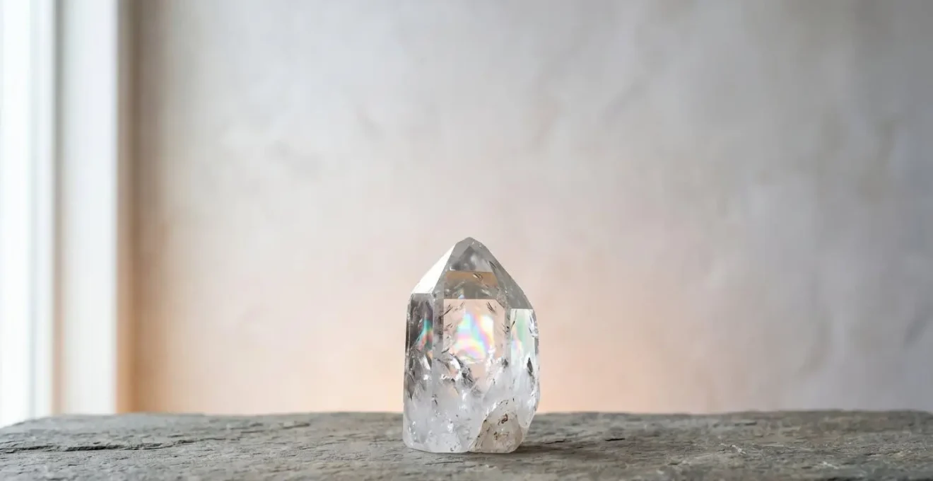 Cristal de roche à terminaison parfaite capturant la lumière naturelle dans un environnement méditatif minimaliste