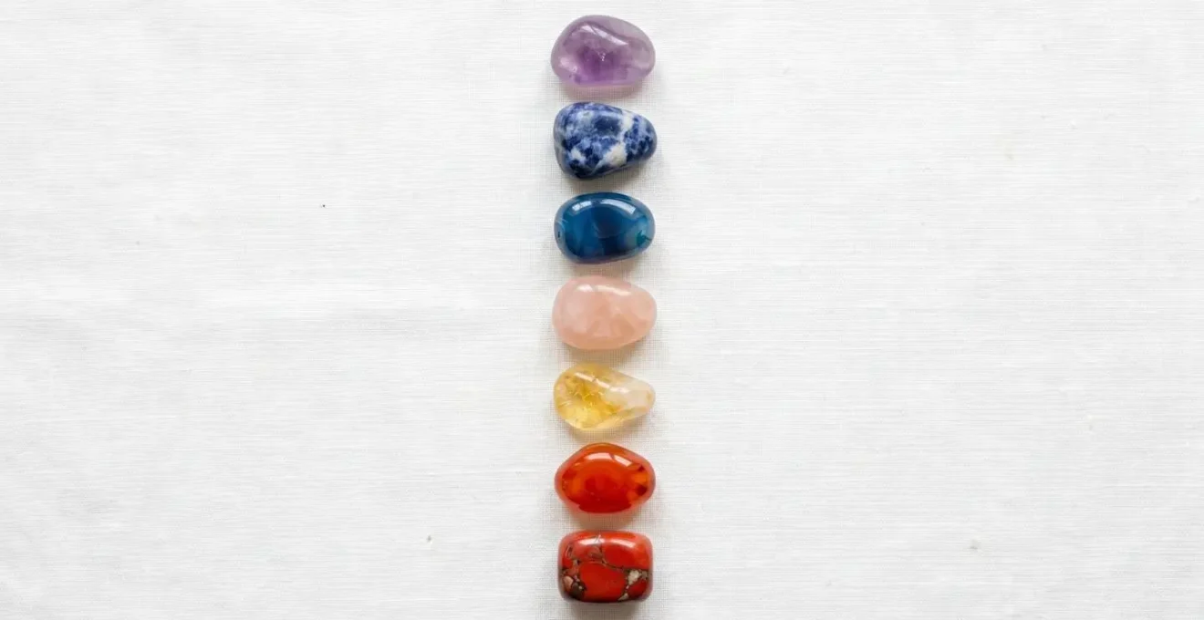 Arrangement harmonieux de sept pierres polies colorées disposées sur le corps selon les points des chakras pour rééquilibrage énergétique