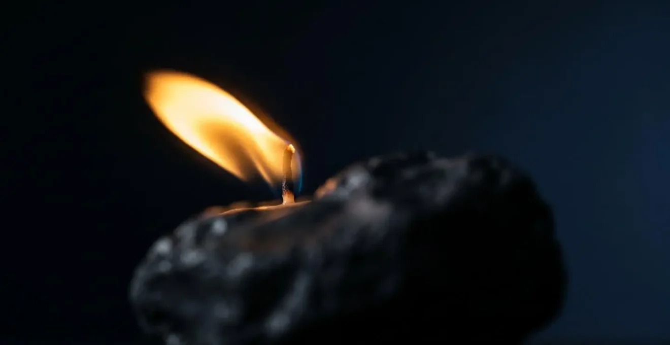 Gros plan sur une flamme de bougie avec une pierre naturelle sombre en avant-plan flou