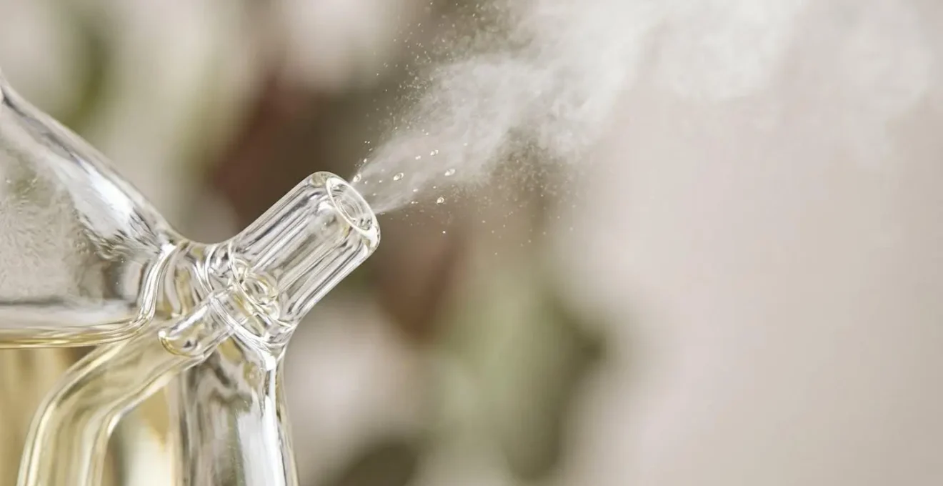 Gros plan sur la verrerie d'un diffuseur par nébulisation en action avec micro-gouttelettes d'huiles essentielles pures